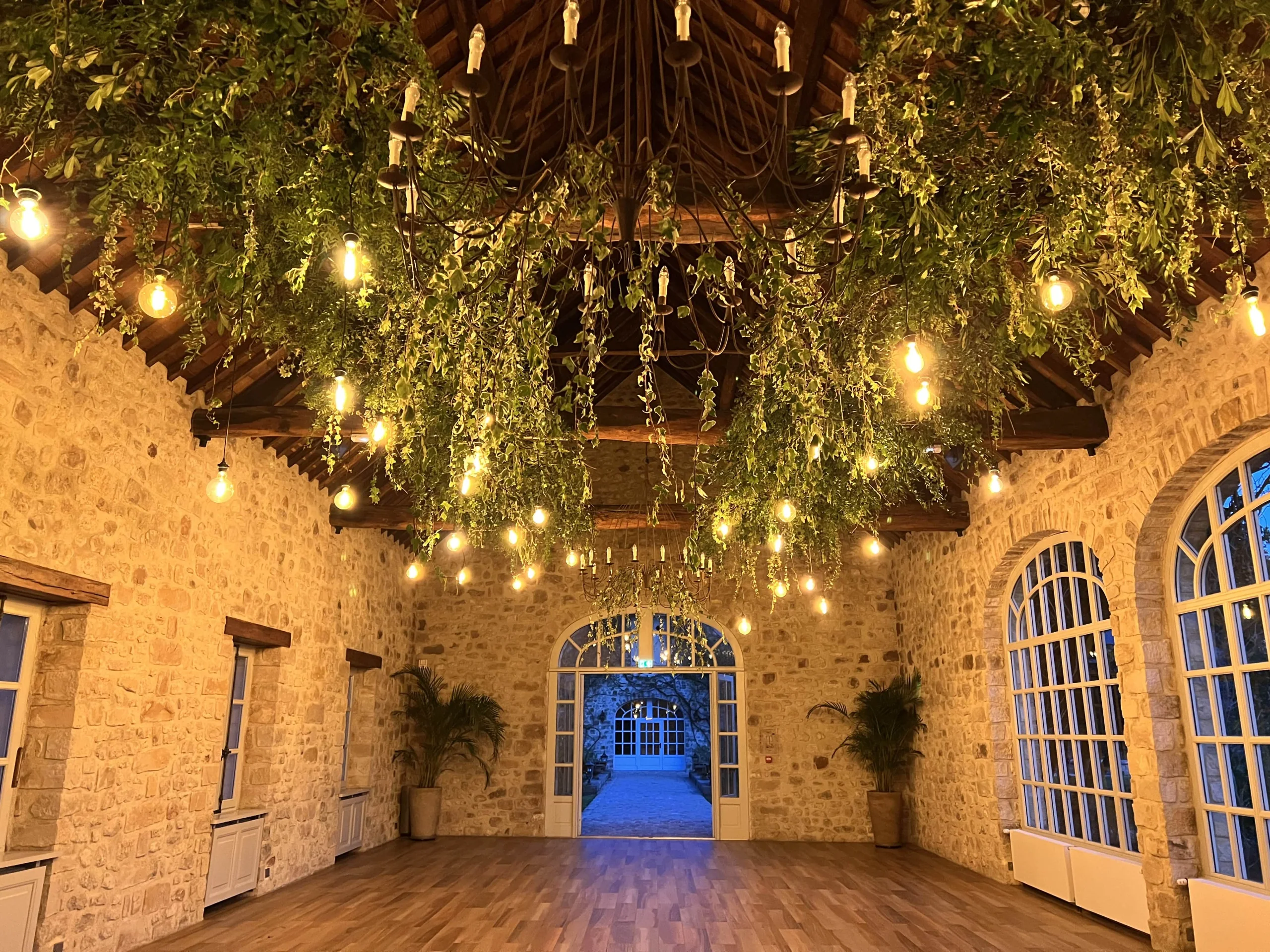 Cour en pierre illuminée de guirlandes et de feuillage pour une réception de mariage – Armony's Déco