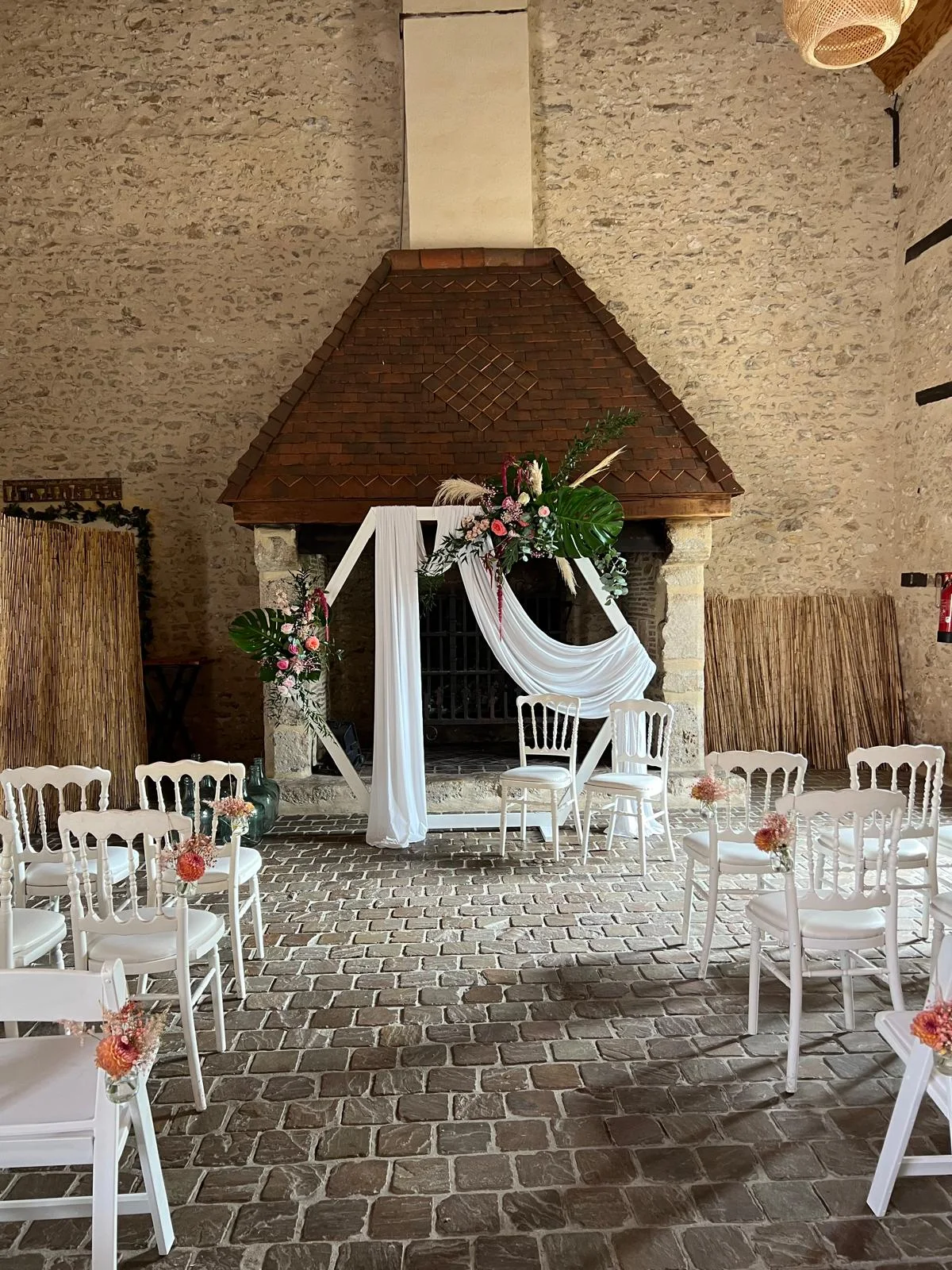 Cérémonie sous un préau : arche blanche, voilages et chaises blanches – Armony's Déco