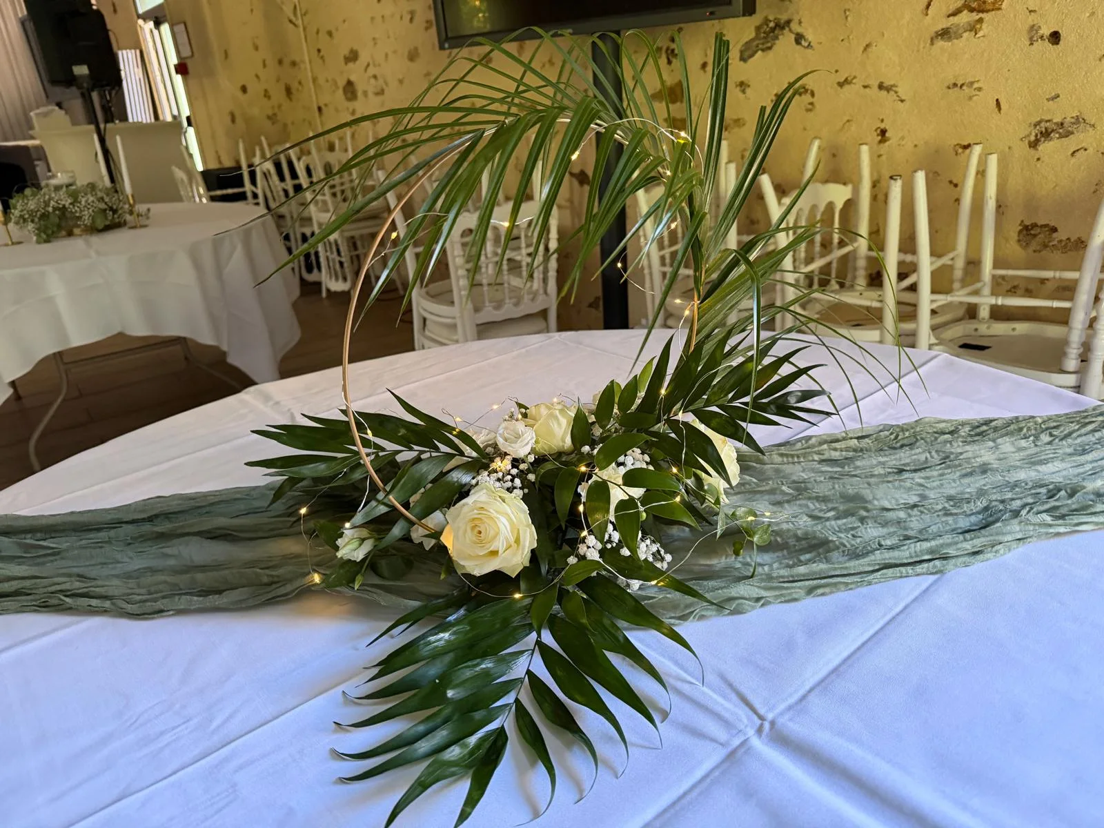 Composition de palmes et roses blanches sur chemin de table vert sauge – Armony's Déco