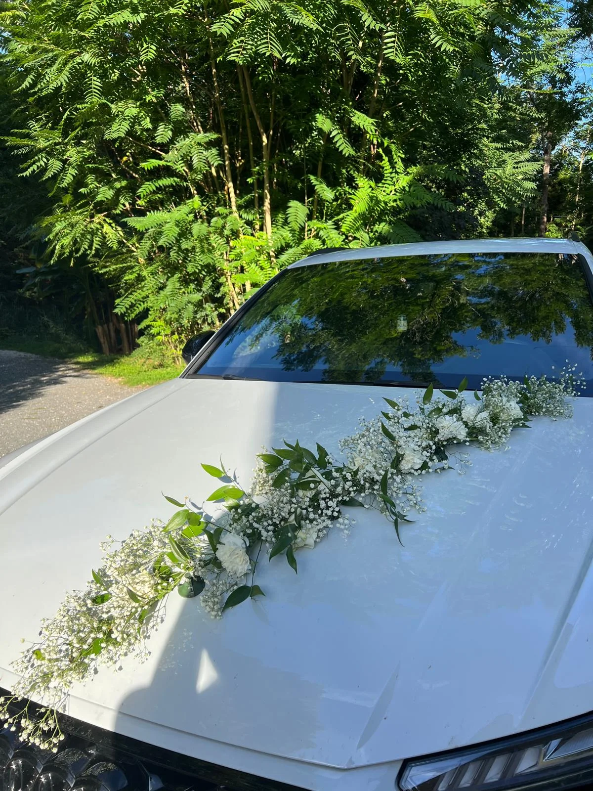 Voiture des mariés décorée d'une guirlande de fleurs blanches – Armony's Déco