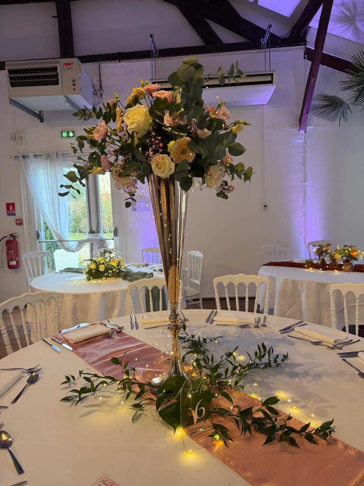 Centre de table haut sur vase flûte doré, roses et eucalyptus – Armony's Déco