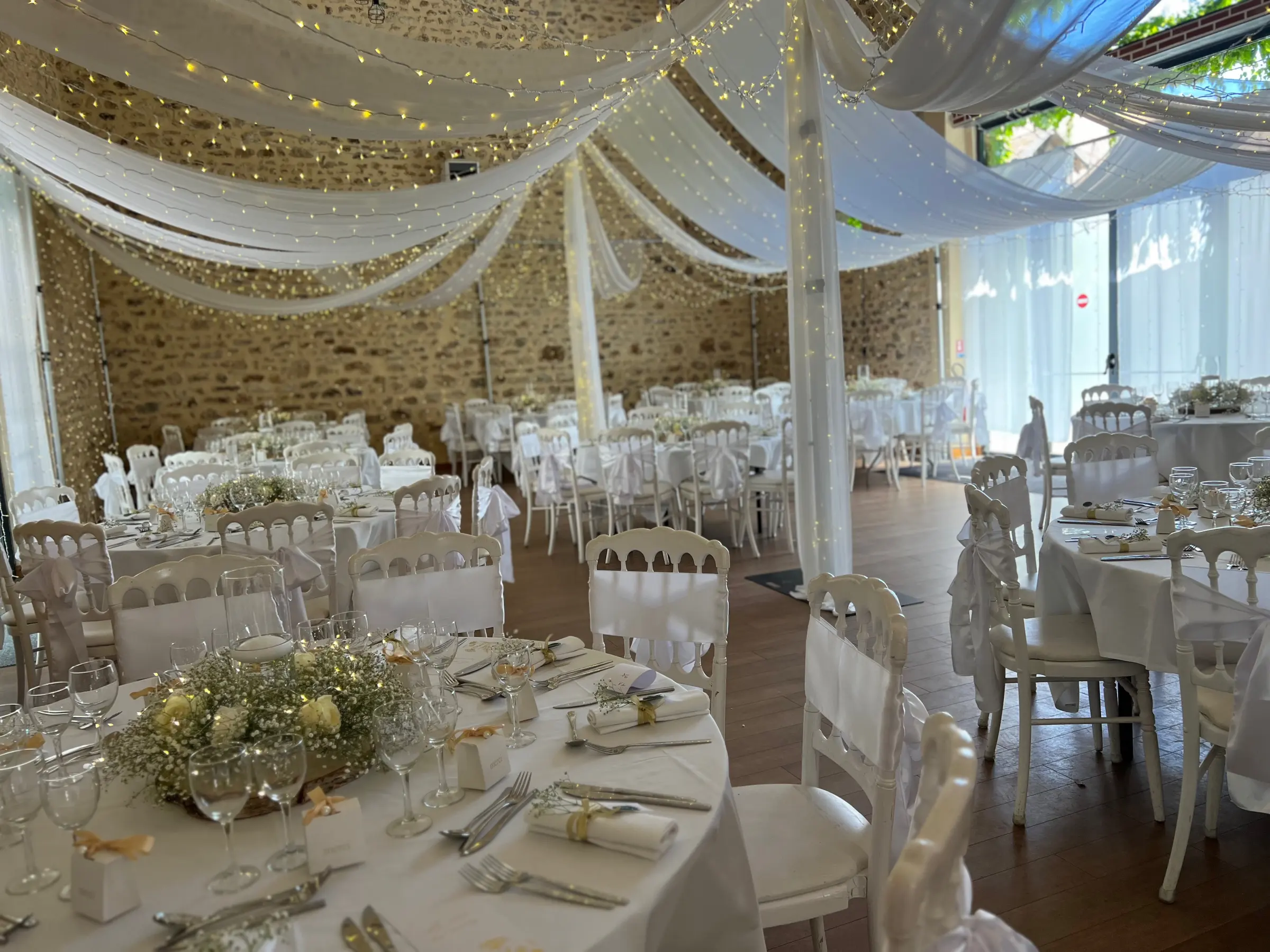 Salle de réception de mariage décorée de voilages et de compositions florales