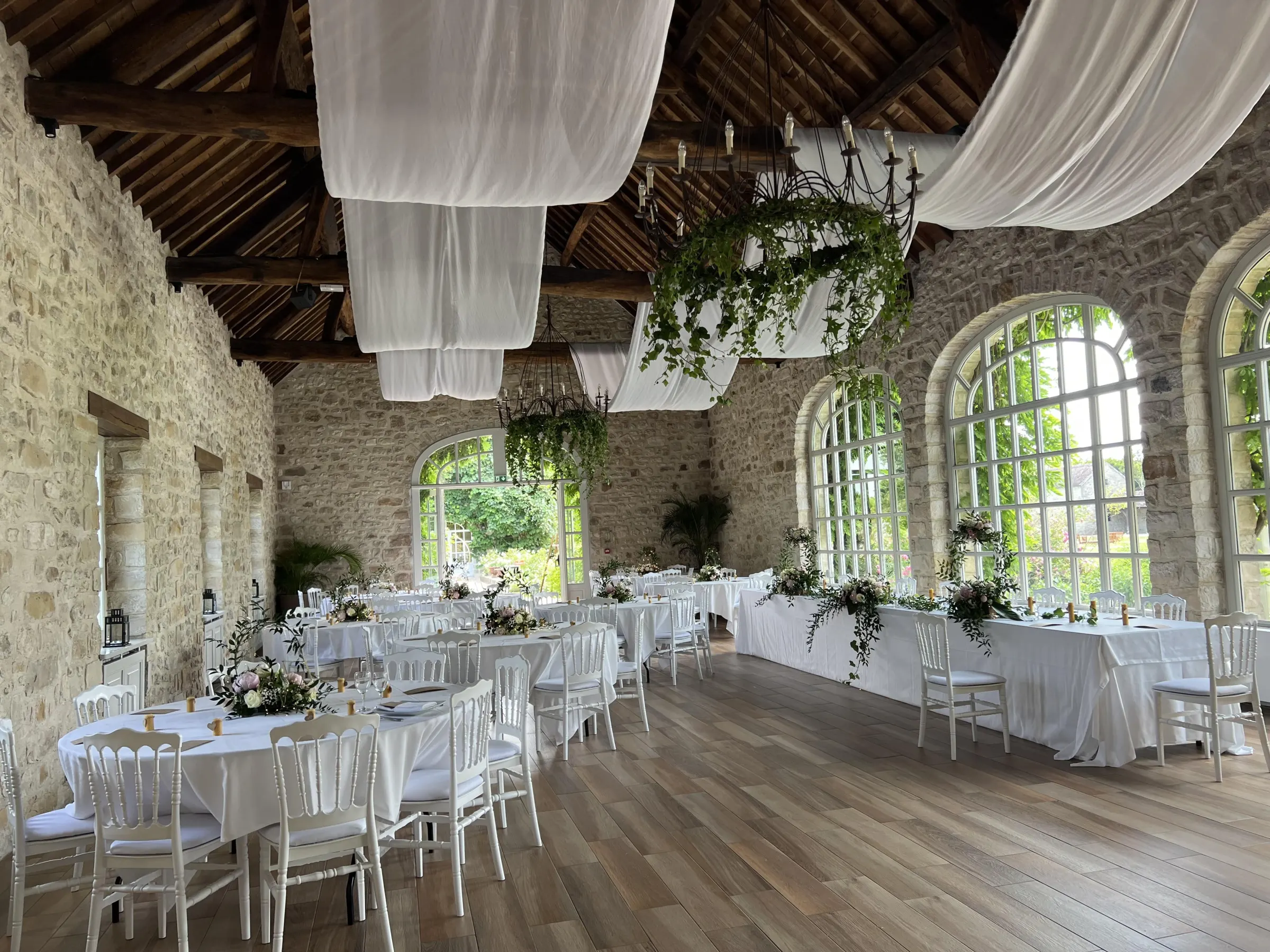 Salle en pierre décorée de voilages et d'une table d'honneur fleurie – Armony's Déco