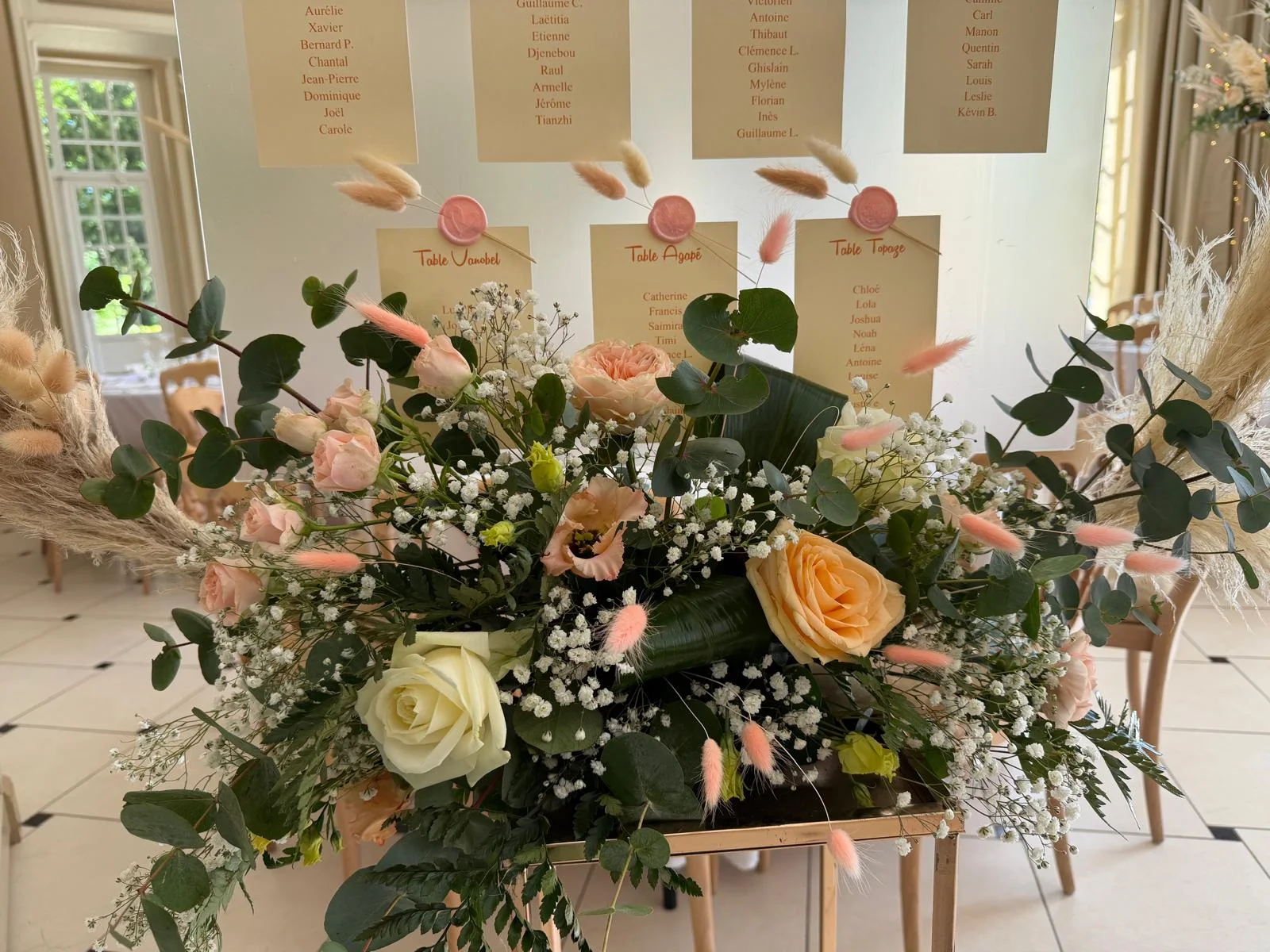 Table d’honneur fleurie de roses et d’eucalyptus devant le plan de table – Armony's Déco