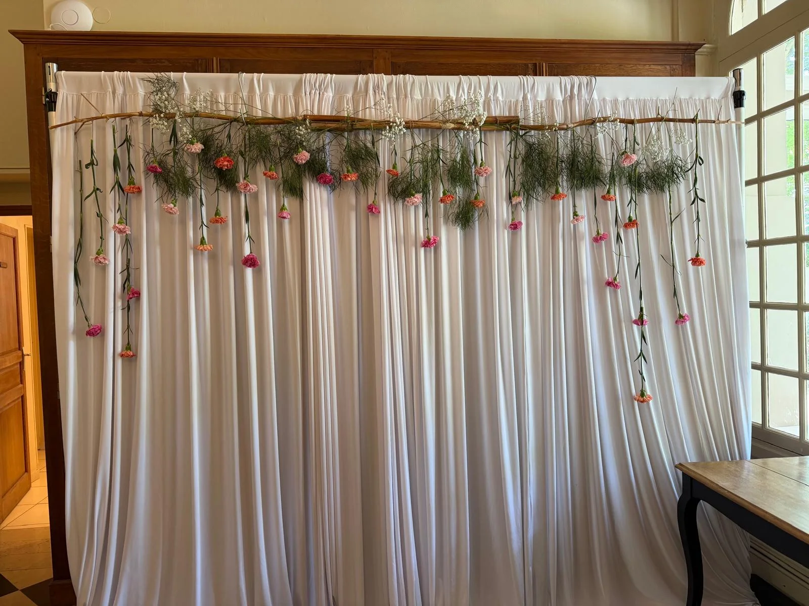Photobooth : toile de fond blanche et guirlande de fleurs suspendues à une branche – Armony's Déco