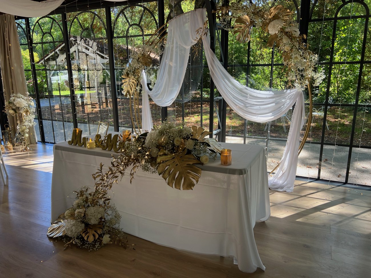 Décoration de mariage : Table d'honneur avec cascade de fleurs et arche fleurie à l'arrière